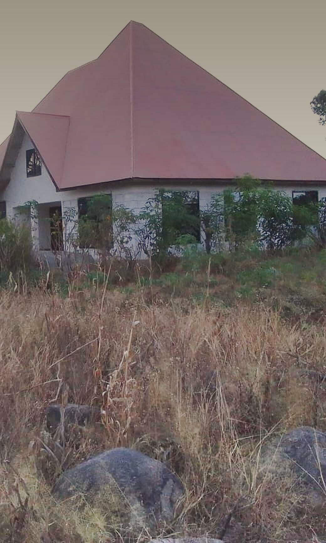 Originalfoto aus Mwanza: das Haus von Hand in Hand mit rotem Dach auf dem Felshügel, daneben der bemalte anamed-Fels